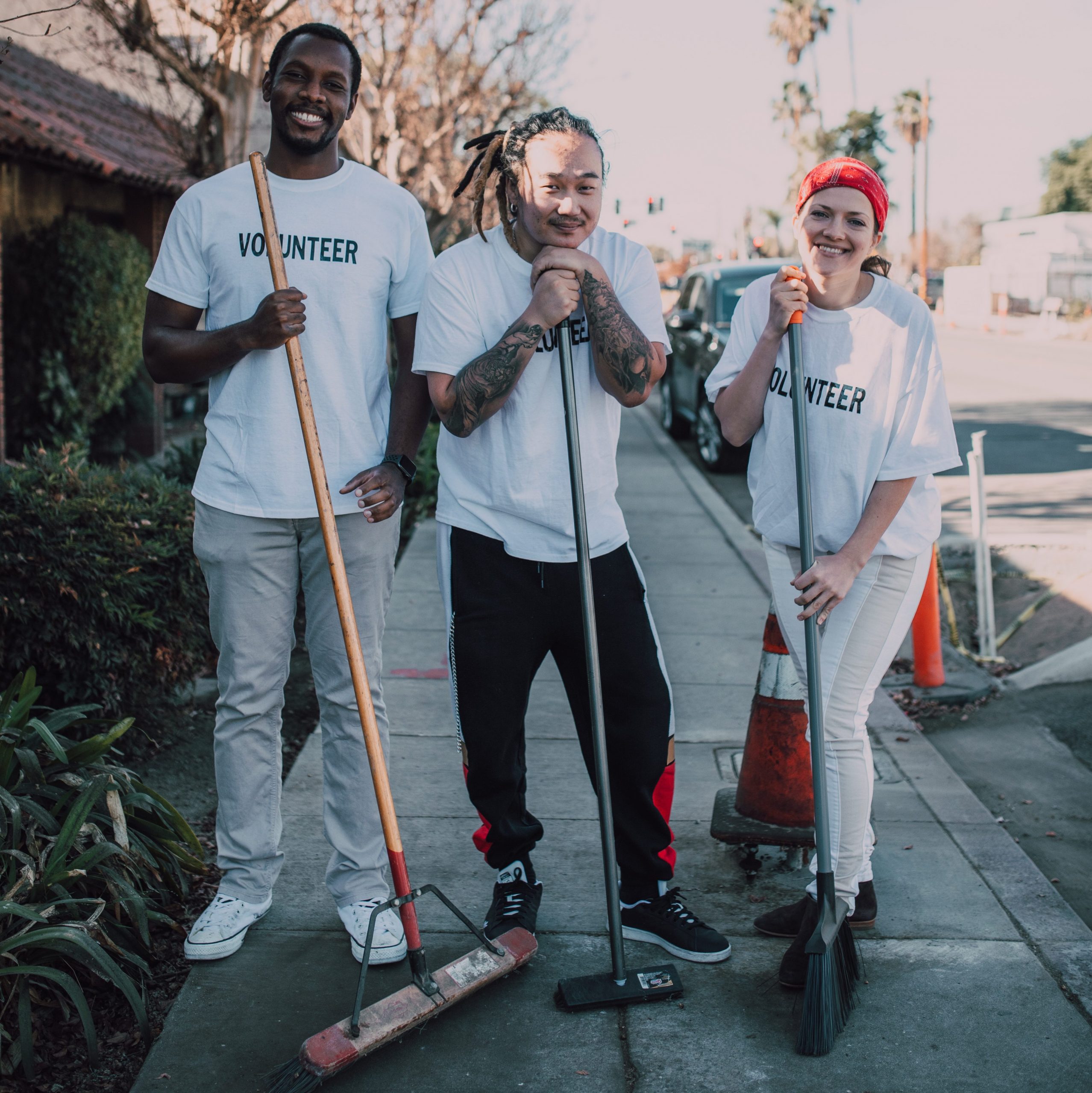 Volunteers sweeping street and smiling